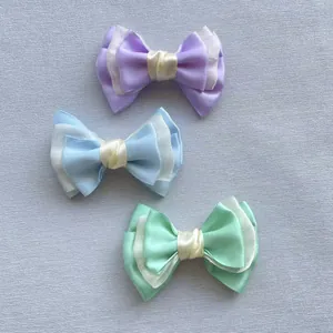 Detailopname van drie gelaagde gaasstrikken in pastelpaars, blauw en groen