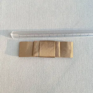 Detail of satin bow accessory in champagne gold with three-layer design and size ruler