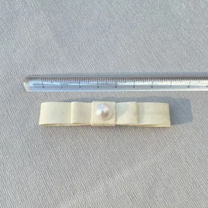 Close-up of 8cm ivory satin double-layered bow with large pearl detail and measurement scale