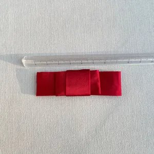 Detail of a red satin multi-layer bow accessory with an 8cm scale measurement