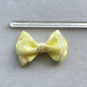 Detailweergave van de gele meerlaagse stoffen strik van 8 cm voor DIY-accessoires