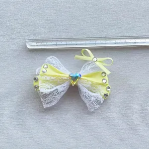 Dettaglio fiocco giallo da 8,5cm con pizzo bianco e cristallo centrale a forma di cuore