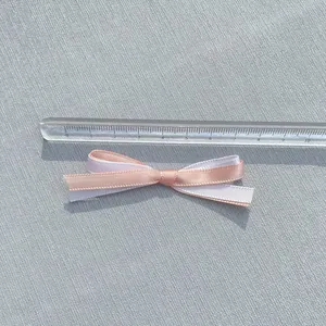 Detail einer 5cm zweilagigen Schleife aus rosa und weißem Satin mit Größenmaßstab