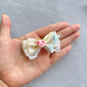 Detail einer cremefarbenen Satinschleife mit Spitze und rosa Erdbeer-Accessoire