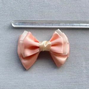 Detailopname van de gelaagde roze en witte gaasstrik met een liniaal voor de afmeting
