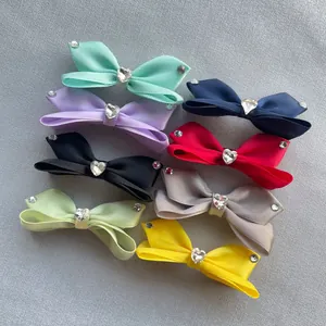 Dettaglio di fiocchi in raso colorati con strass a forma di cuore e piccole gemme