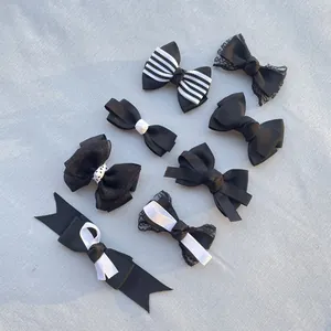 Flat lay of seven black and white handmade bows in various ribbon and lace designs