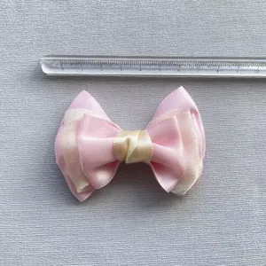 Detailopname van een 7 cm roze en crème satijnen strik met meetlat voor de juiste afmeting