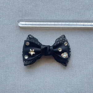 Dettaglio di un fiocco in pizzo nero da 7 cm con strass lucidi e raso morbido