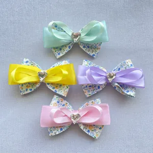 Détail de nœuds en tissu floral DIY avec ruban de satin et strass en cœur au centre