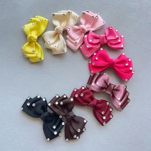 Flat lay of nine colorful ribbed ribbon bows with sparkling rhinestone accents on grey fabric
