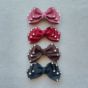 Detail of four ribbon bow hair clips with rhinestones in pink, red, brown, and black