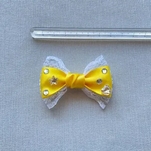 Dettaglio fiocco fatto a mano da 5,5 cm in raso giallo e pizzo con strass scintillanti