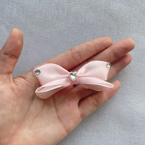 Dettaglio di fiocco in raso rosa con strass a cuore per accessori capelli e scarpe