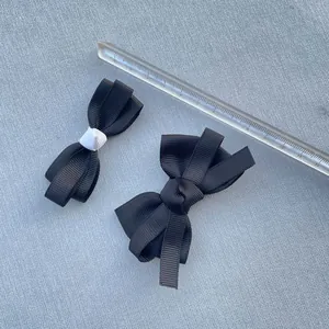 Macro shot showing size measurements of handmade black grosgrain ribbon bows with scale