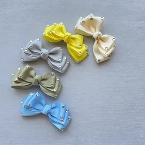 Close-up of five colorful ribbon bows with sparkling rhinestone edges for DIY hair accessories