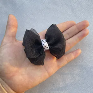 Close-up of handmade black organza bow with polka dot ribbon center for DIY crafts