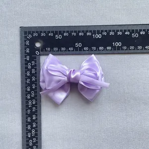 Detailopname van een paarse satijnen strik met afmetingen van 8,5 cm x 5 cm op schaal