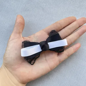 Detail of a handmade black and white bow with lace and ribbed texture held by hand