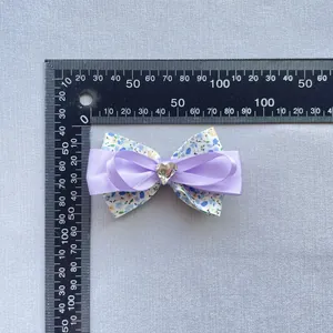 Détail d'un nœud floral fait main montrant une largeur de 8 cm avec règle de mesure