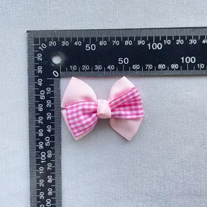 Pink ribbed and checkered bow hair accessory displayed with measurement ruler