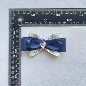 Détail d'un nœud en tissu floral de 80 mm avec satin bleu et gemme en forme de cœur