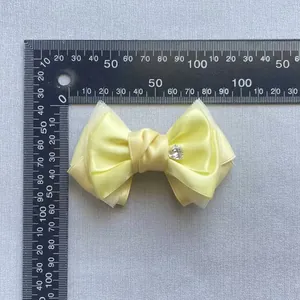 Detail showing 10cm yellow satin and mesh bow with heart crystal rhinestone measuring scale