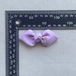 Close-up of a purple grosgrain ribbon bow with star crystal being measured by a ruler