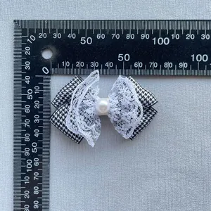 Houndstooth bow accessory with white lace trim and faux pearl detail for DIY crafts