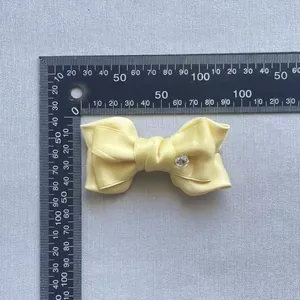 Detail view of yellow satin bow accessory with heart crystal and measurement scale