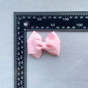 Close-up of 80mm baby pink grosgrain ribbon bow with a scale showing size and texture