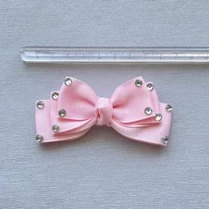 Close-up of pink rhinestone bow hairclip with ribbed texture showing 8cm length scale