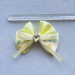 Dettaglio di fiocco in raso giallo 7cm con strass a cuore e pois verdi