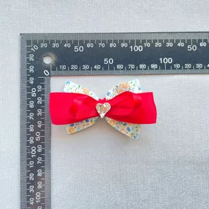 Détail d'un nœud en satin rouge à fleurs avec cœur en cristal, mesurant 8,5 cm