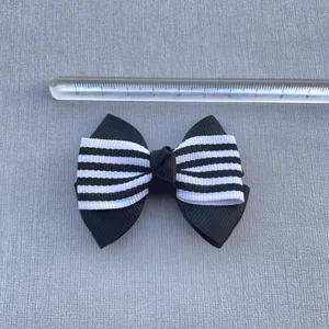 Detail view of 8.5cm black and white striped grosgrain bow with ruler for scale