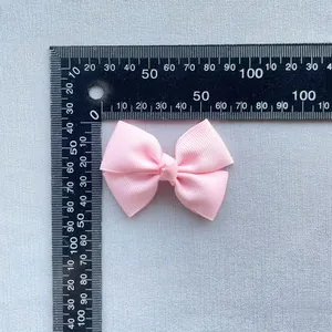 Pink ribbed ribbon bow hair accessory measured with a ruler showing 5cm width detail