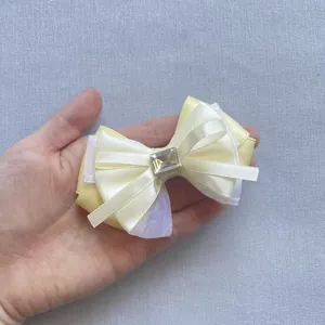Detail of a yellow satin and purple mesh bow with a rectangular crystal center