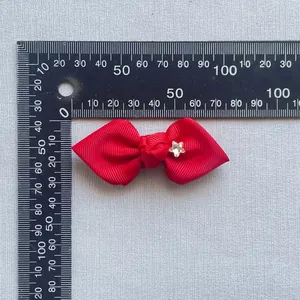 Detailed view of red grosgrain ribbon bow with star rhinestone on measuring scale
