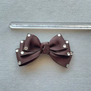 Brown grosgrain ribbon bow accessory with sparkling rhinestones and size reference scale
