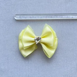 Dettaglio del fiocco giallo multistrato con gemma a cuore e righello che misura 8,5 cm