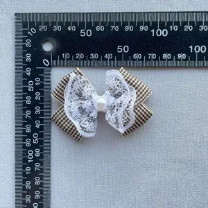 Detail view of plaid bow accessory with white lace and center pearl for DIY crafts