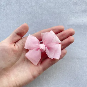 Detailed view of a pink ribbed organza double-layered bow held in palm for size scale