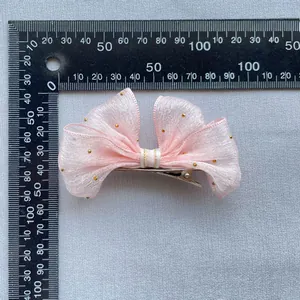Pink mesh butterfly hair clip with golden sparkles shown with measuring scale