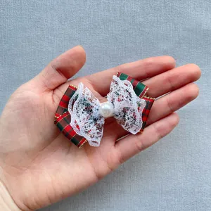 Close-up of a red and green plaid bow hair clip with white lace and pearl detail