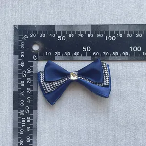 Close-up of a navy mesh bow hairclip with houndstooth ribbon and a square rhinestone