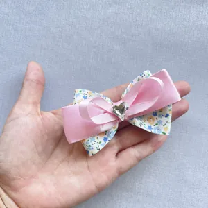 Détail d'un nœud en satin rose et tissu floral avec cristal en forme de cœur