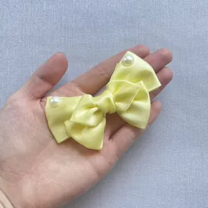 Detail of yellow velvet bow hair accessory with decorative pearls on a purple background
