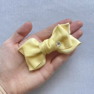 Detail of yellow satin bow with a sparkling heart-shaped crystal center held by hand
