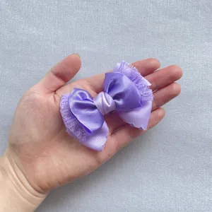 Detailweergave van de meerlagige paarse satijnen en kanten strik voor haar en poppendecor