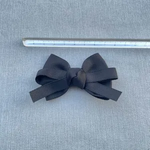 Detailed view of an 8.5cm black grosgrain ribbon bow with a ruler for scale measurements